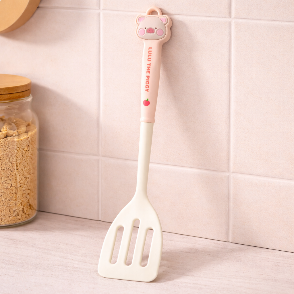Cute silicone slotted spatula with cartoon pig handle, pastel kitchen cooking utensil for baking and frying.