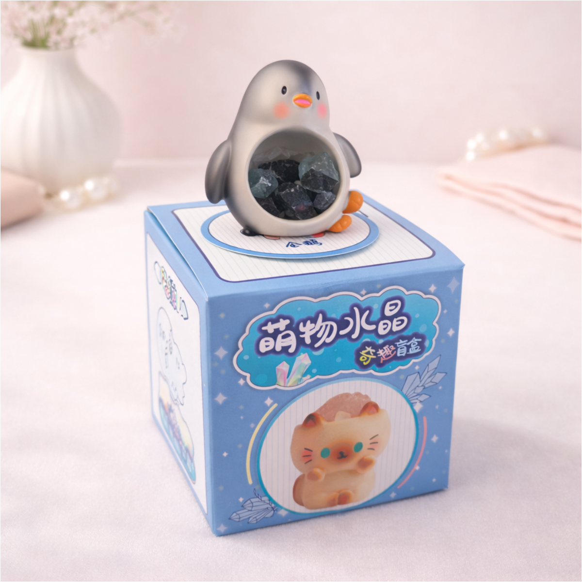 Cute penguin figurine holding a stone on display box, kawaii animal collectible for desk and shelf decor.