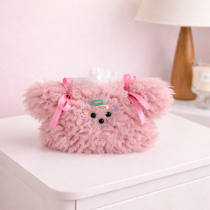 Pink fluffy plush tissue holder with ribbon bows and cute face details, cozy kawaii tissue box cover for desk or bedside.
